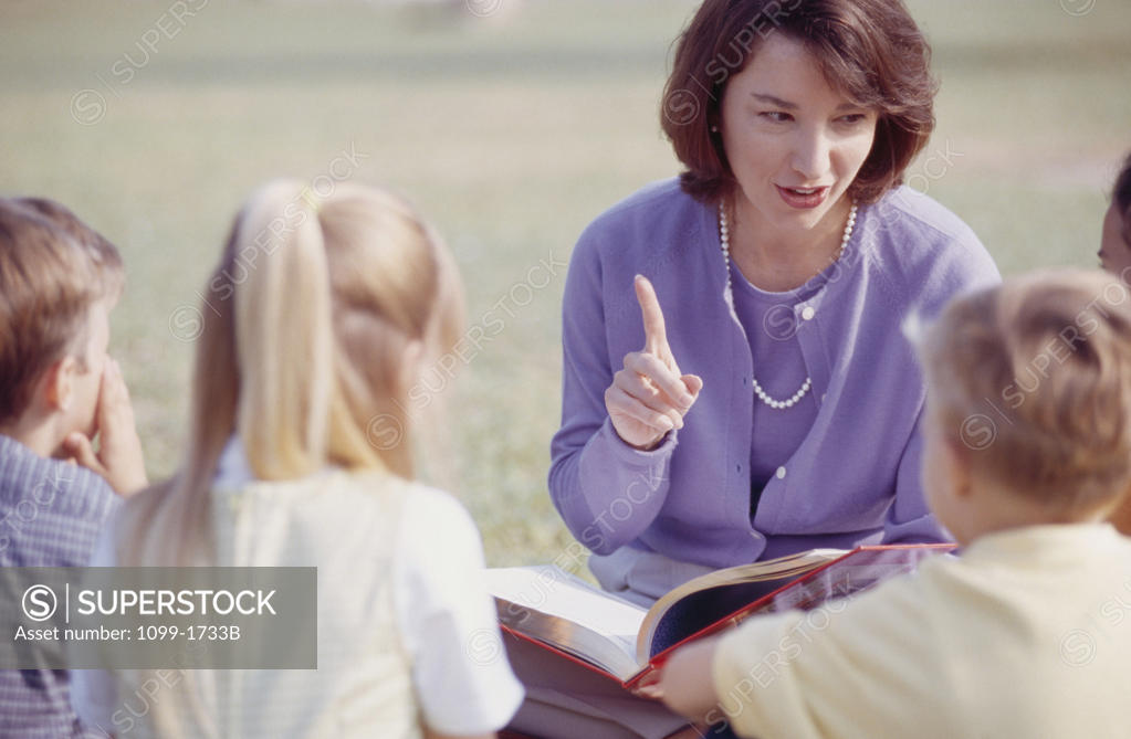 Stock Photo: 1099-1733B Female teacher sitting with her students and pointing upwards