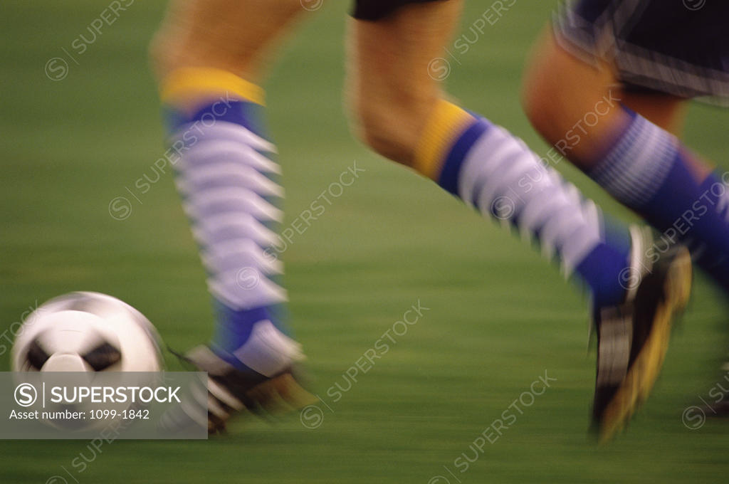 Stock Photo: 1099-1842 Low section view of a soccer player running with a soccer ball