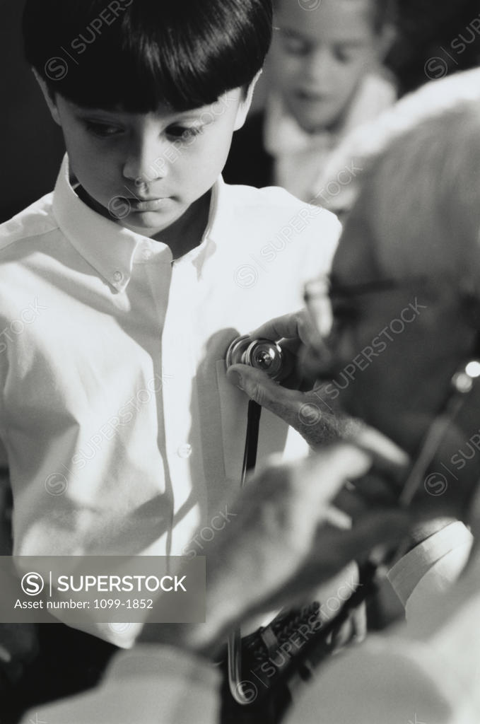 Stock Photo: 1099-1852 Male doctor listening to a boy's heartbeat