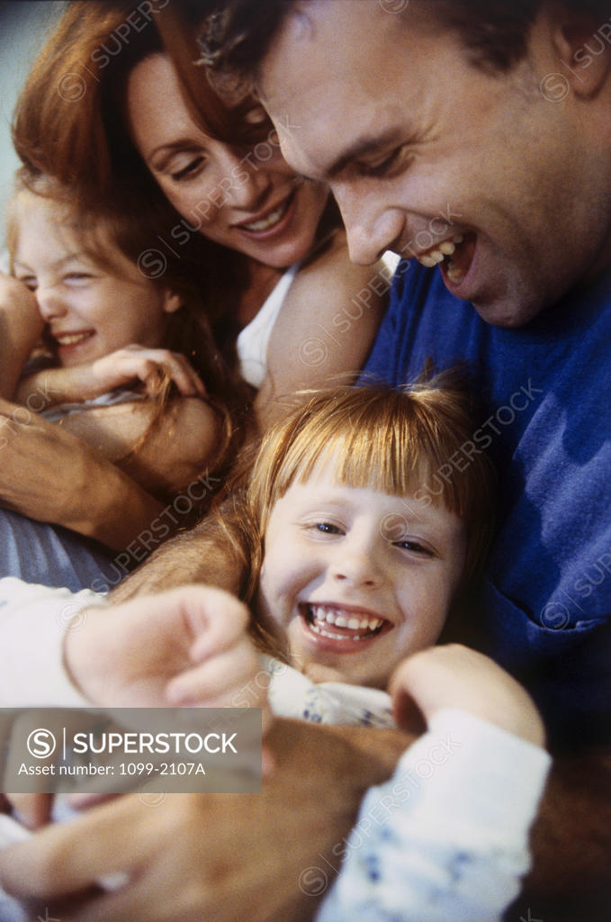 Stock Photo: 1099-2107A Close-up of a mid adult couple hugging their daughters and smiling