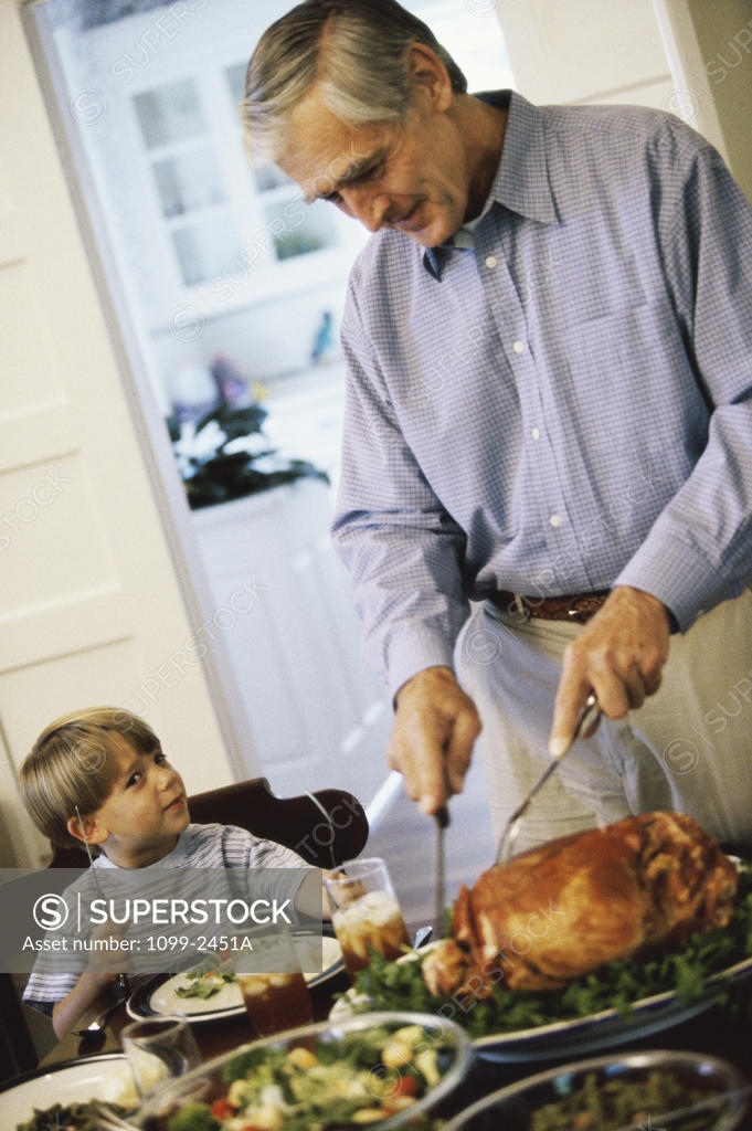 Stock Photo: 1099-2451A Grandfather slicing a turkey