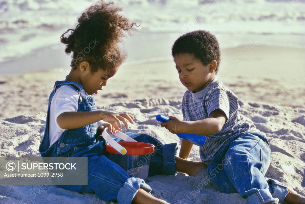 Stock Photo: 1099-2958 Boy and a girl playing with a sand pail and a shovel on the beach