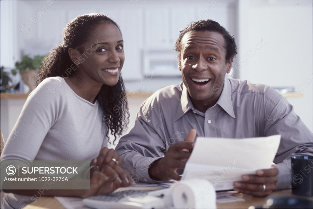 Stock Photo: 1099-2976A Portrait of a mid adult couple holding a document and smiling