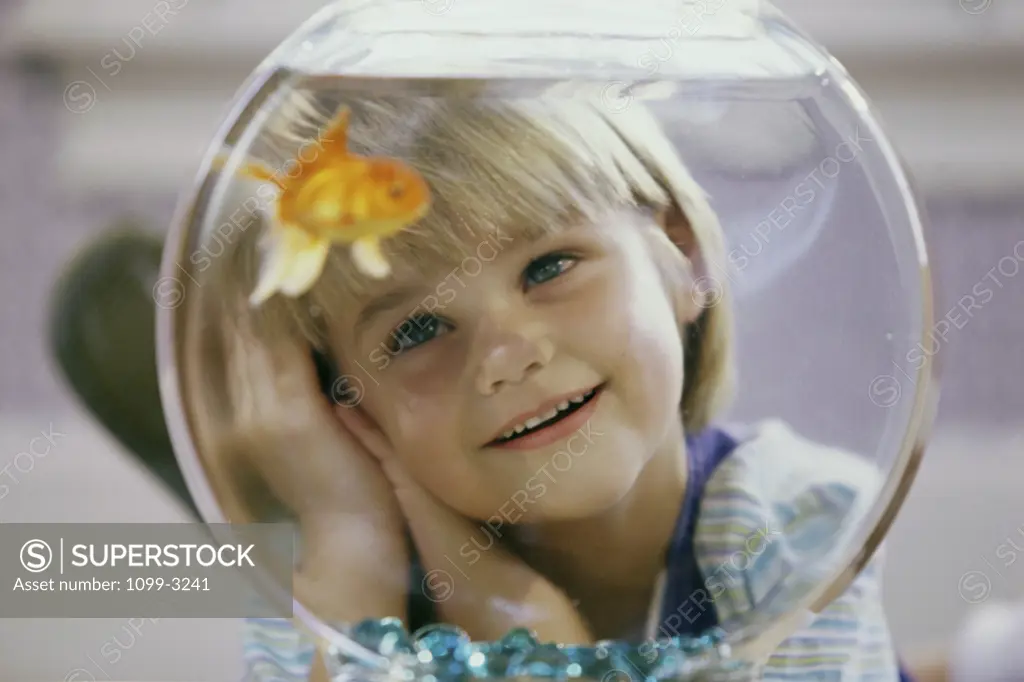 Close-up of a girl watching a goldfish in a fishbowl