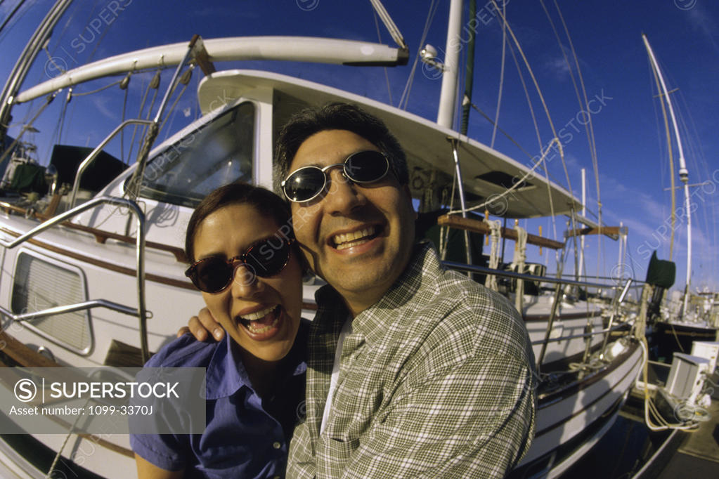 Stock Photo: 1099-3370J Portrait of a young couple standing near a sailboat