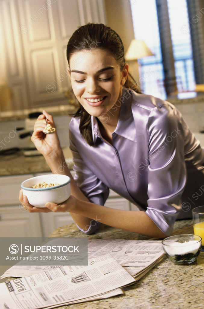 Stock Photo: 1099-3582C Young woman holding a bowl of cereal smiling
