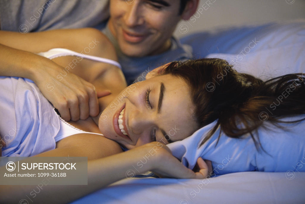 Stock Photo: 1099-3618B Young couple lying on a bed laughing