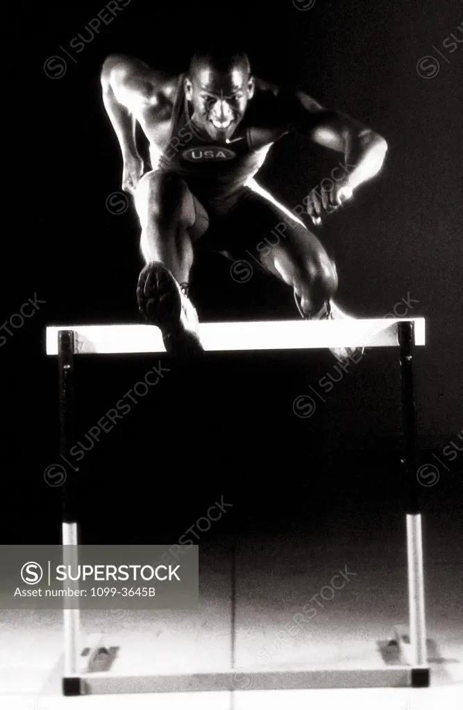 Portrait of a young man jumping over a hurdle