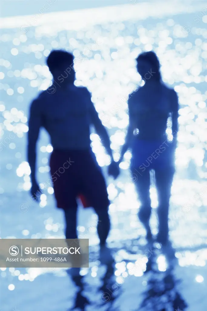 Silhouette of a young couple walking on the beach