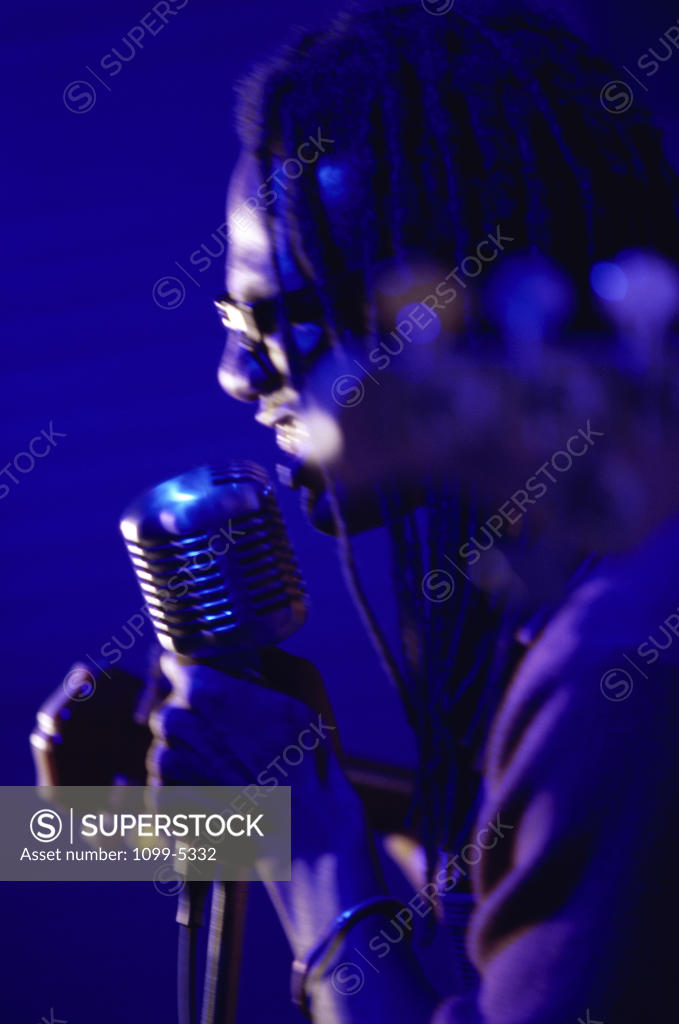 Stock Photo: 1099-5332 Side profile of a young man singing into a microphone