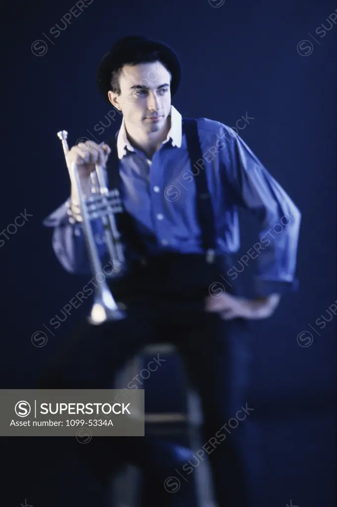 Young man sitting on a stool holding a trumpet