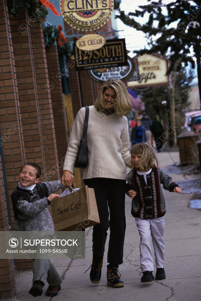 Stock Photo: 1099-5456B Mother walking with her two children on the sidewalk