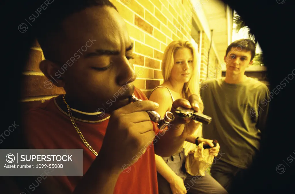 Side profile of a group of teenagers smoking opium in a pipe