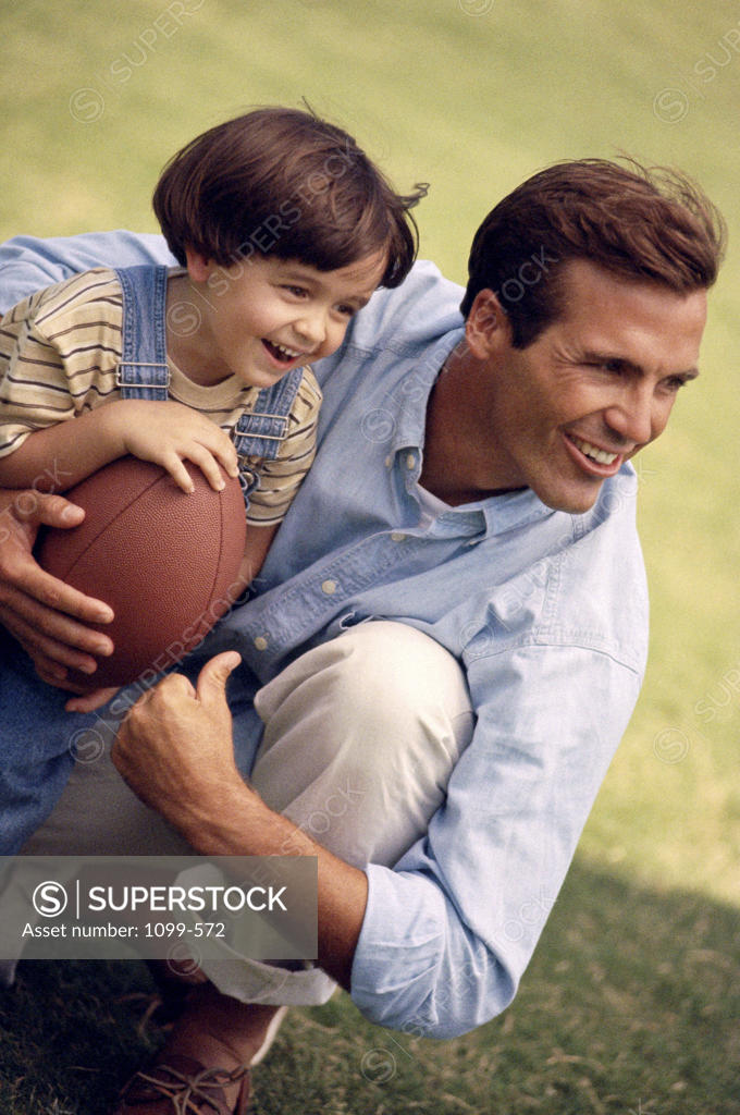 Stock Photo: 1099-572 Father holding his daughter and a football