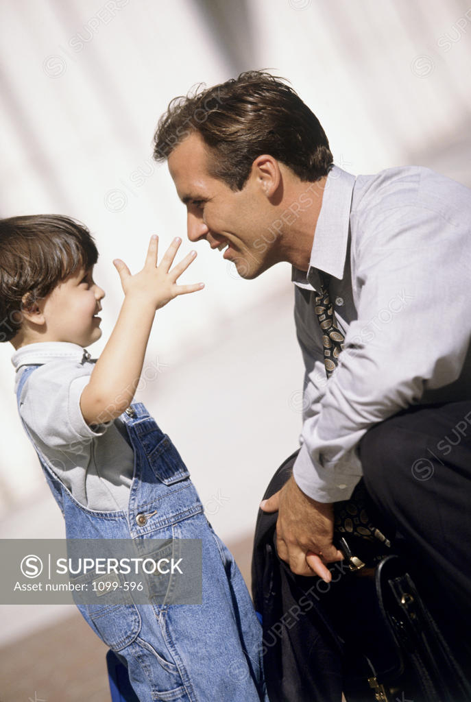 Stock Photo: 1099-596 Side profile of a mid adult man and his son looking at each other and smiling