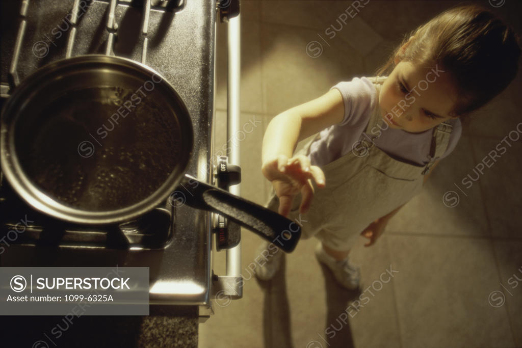 Stock Photo: 1099-6325A Girl reaching for a pan on a stove