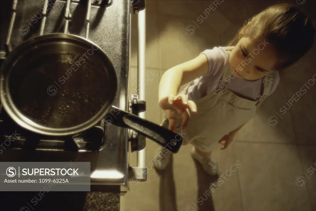 Girl reaching for a pan on a stove