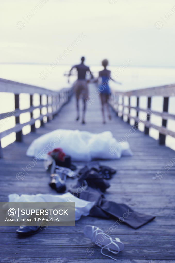 Stock Photo: 1099-6515A Young couple running in swimwear on a pier