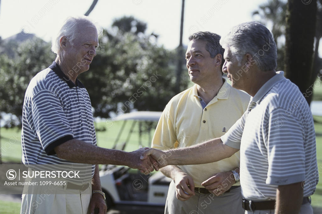 Stock Photo: 1099-6655 Close-up of three senior men shaking hands on a golf course