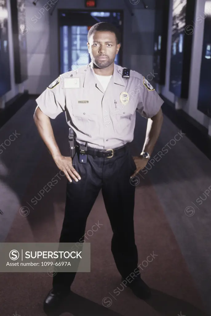 Portrait of a male security guard standing with arms akimbo