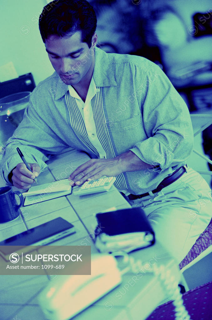 Stock Photo: 1099-689 High angle view of a mid adult man calculating bills