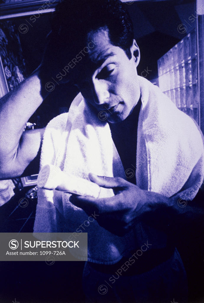 Stock Photo: 1099-726A Young man holding a pill bottle