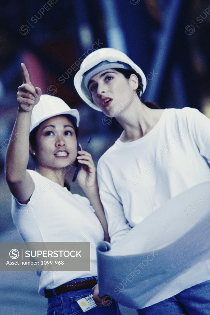Stock Photo: 1099-968 Two female construction workers pointing at a construction site