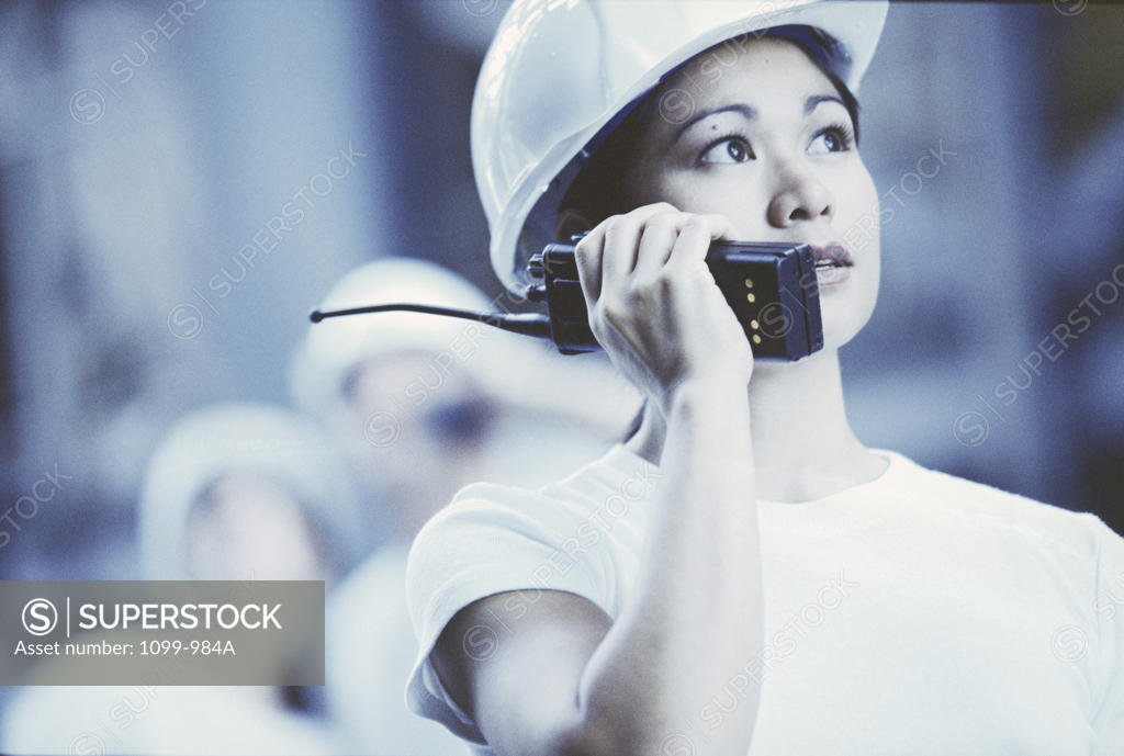 Stock Photo: 1099-984A Female construction worker talking on a walkie-talkie looking up