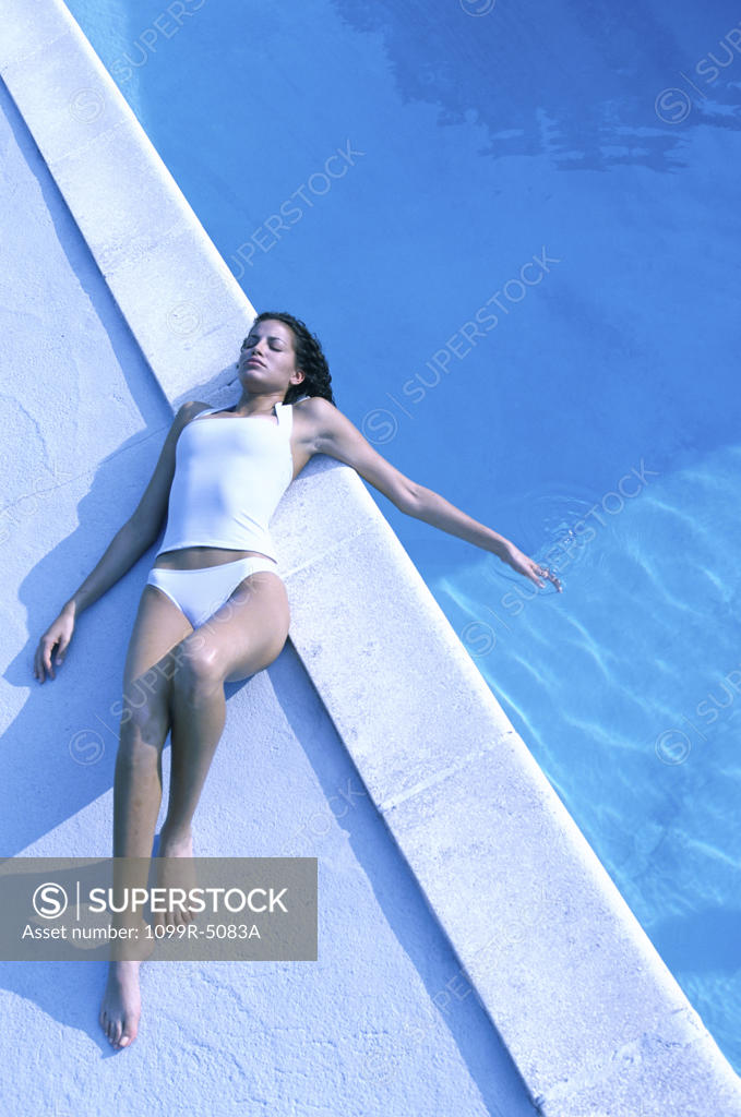 Stock Photo: 1099R-5083A High angle view of a young woman lying near a swimming pool