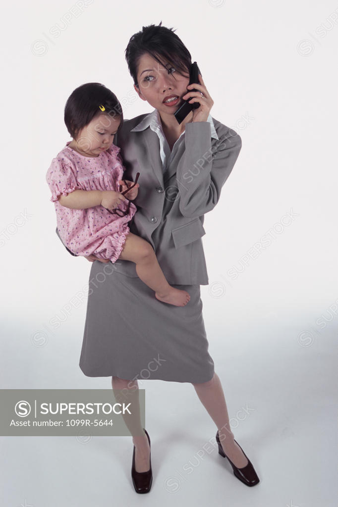 Stock Photo: 1099R-5644 Portrait of a mother carrying her daughter talking on a mobile phone
