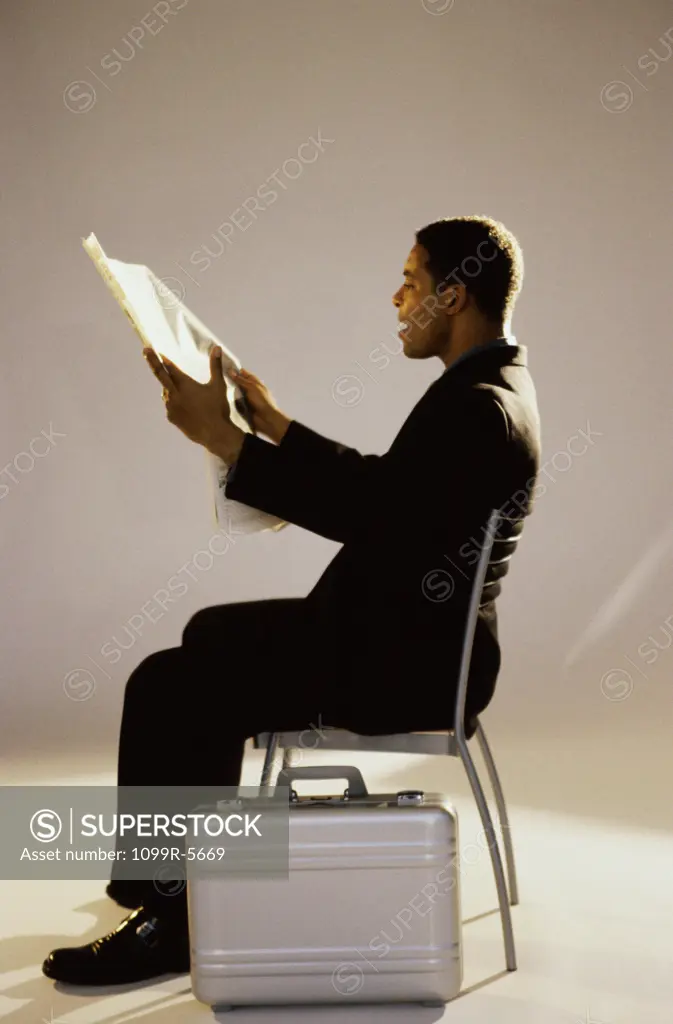 Businessman reading a newspaper sitting on a chair