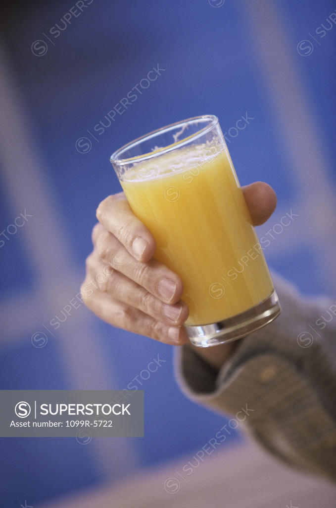 Stock Photo: 1099R-5722 Person holding a glass of orange juice