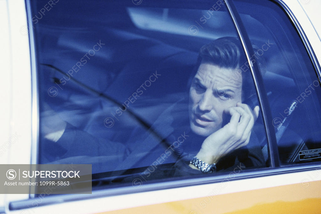 Stock Photo: 1099R-5863 Businessman sitting in a taxi talking on a mobile phone