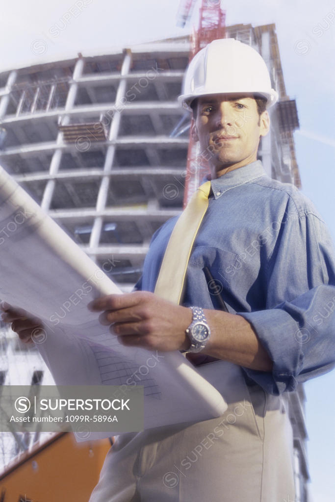 Stock Photo: 1099R-5896A Portrait of an engineer standing at a construction site holding blueprints