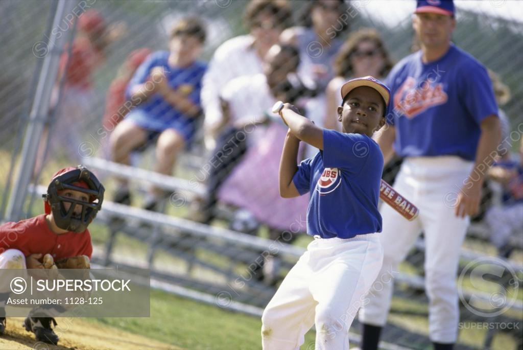 Stock Photo: 1128-125 Boy swinging a baseball bat on a field