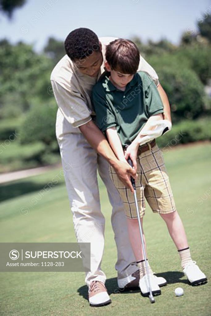 Stock Photo: 1128-283 Young man teaching golf to a teenage boy on a golf course