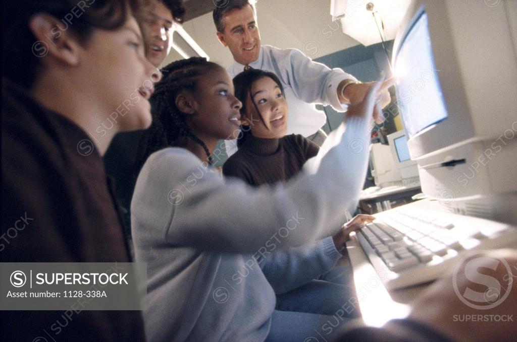 Stock Photo: 1128-338A Low angle view of a male teacher and teenage students in front of a computer