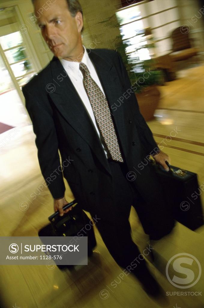 Stock Photo: 1128-576 Businessman walking with luggage in a hotel