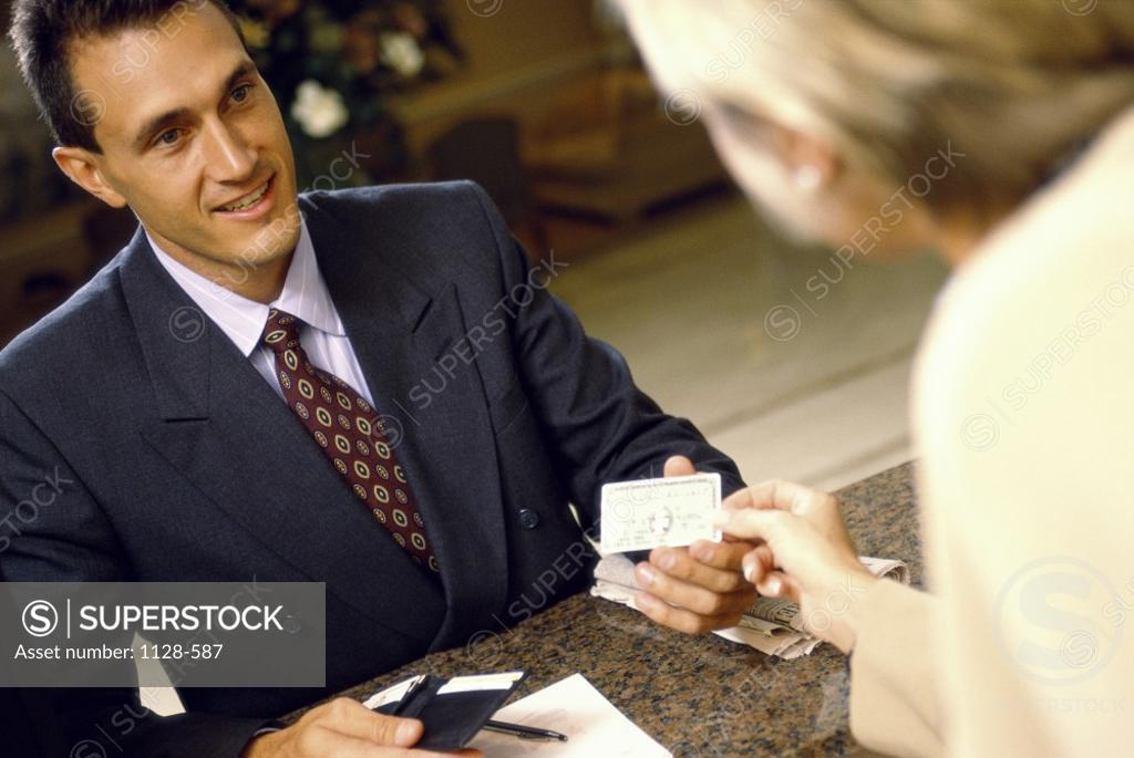 Stock Photo: 1128-587 Hotel clerk handing a credit card to a businessman