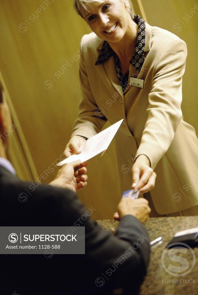 Stock Photo: 1128-588 Hotel clerk handing keys to a businessman