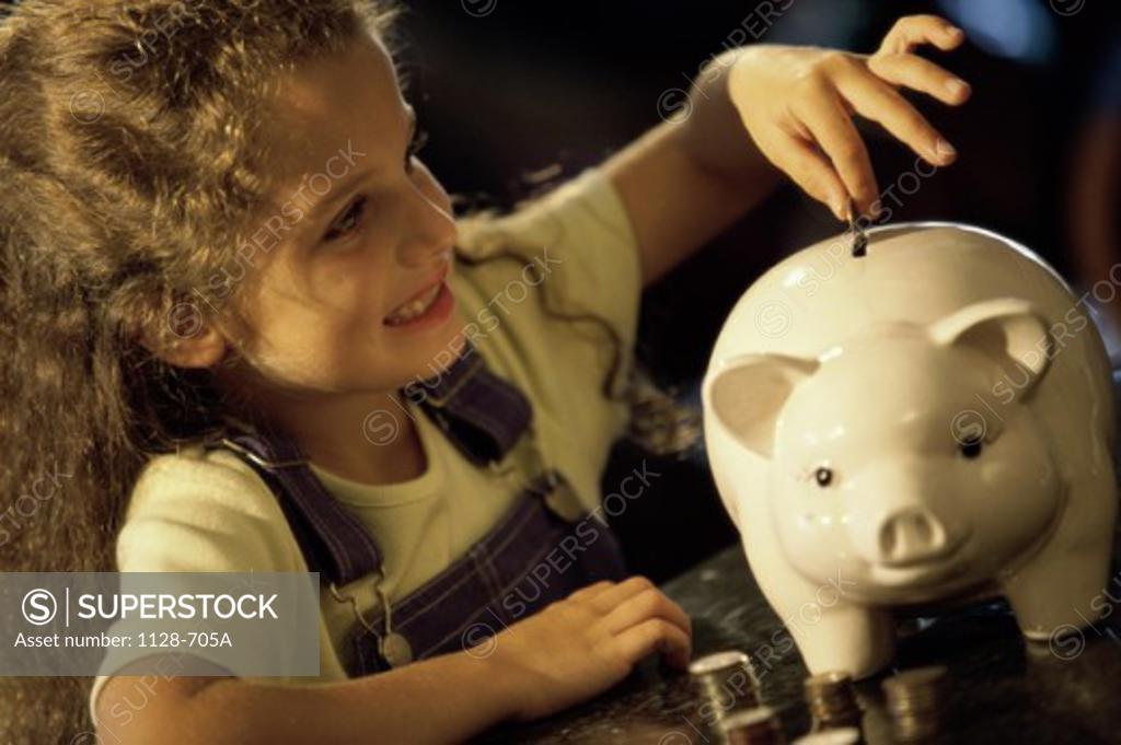 Stock Photo: 1128-705A Girl dropping a coin into a piggy bank