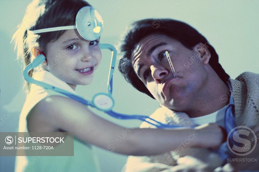 Stock Photo: 1128-720A Portrait of a girl pretending to be a doctor with her father as a patient