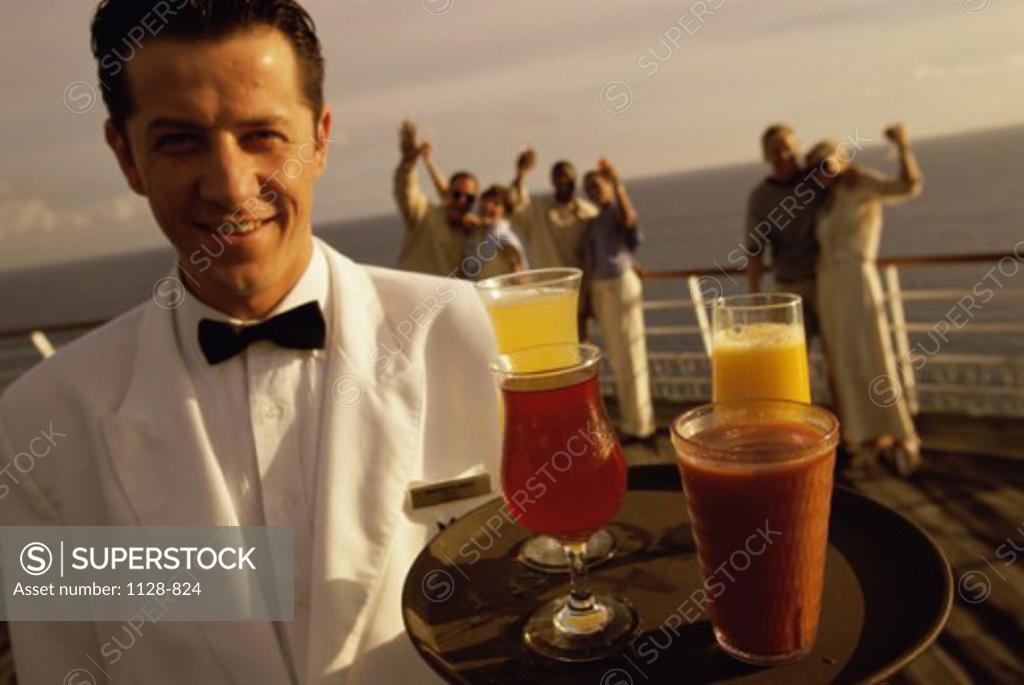 Stock Photo: 1128-824 Portrait of a waiter holding drinks on a tray with a group of people behind him