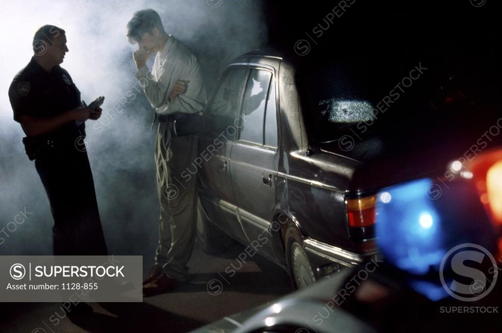 Stock Photo: 1128-855 Policeman talking to a mid adult man at an accident site