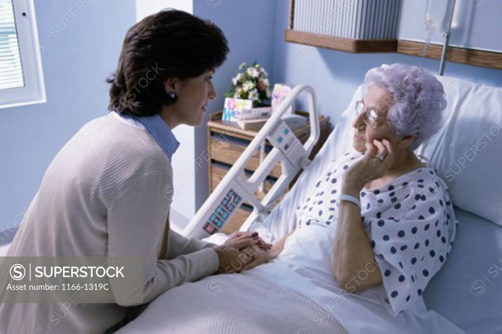 Stock Photo: 1166-1319C Female doctor sitting on a female patient's bed