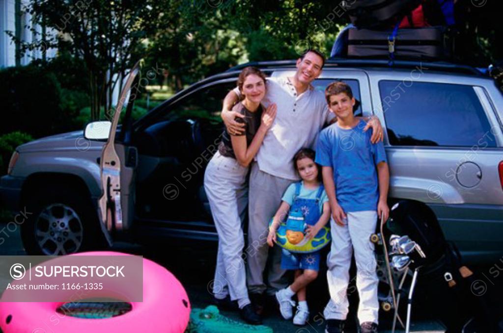 Stock Photo: 1166-1335 Portrait of parents and two children standing with their luggage near a car