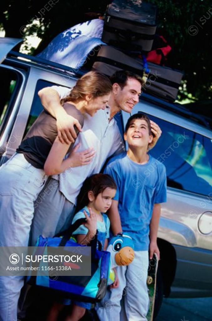 Stock Photo: 1166-1338A Parents and their two children standing with their luggage near a car