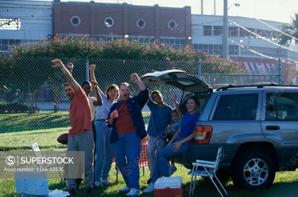 Stock Photo: 1166-1353C Group of people with their hands raised standing behind a vehicle