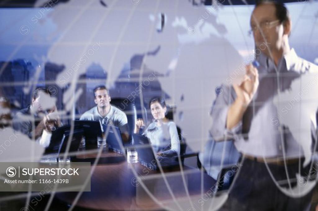 Stock Photo: 1166-1439B Business executives pointing to a world map in a conference room