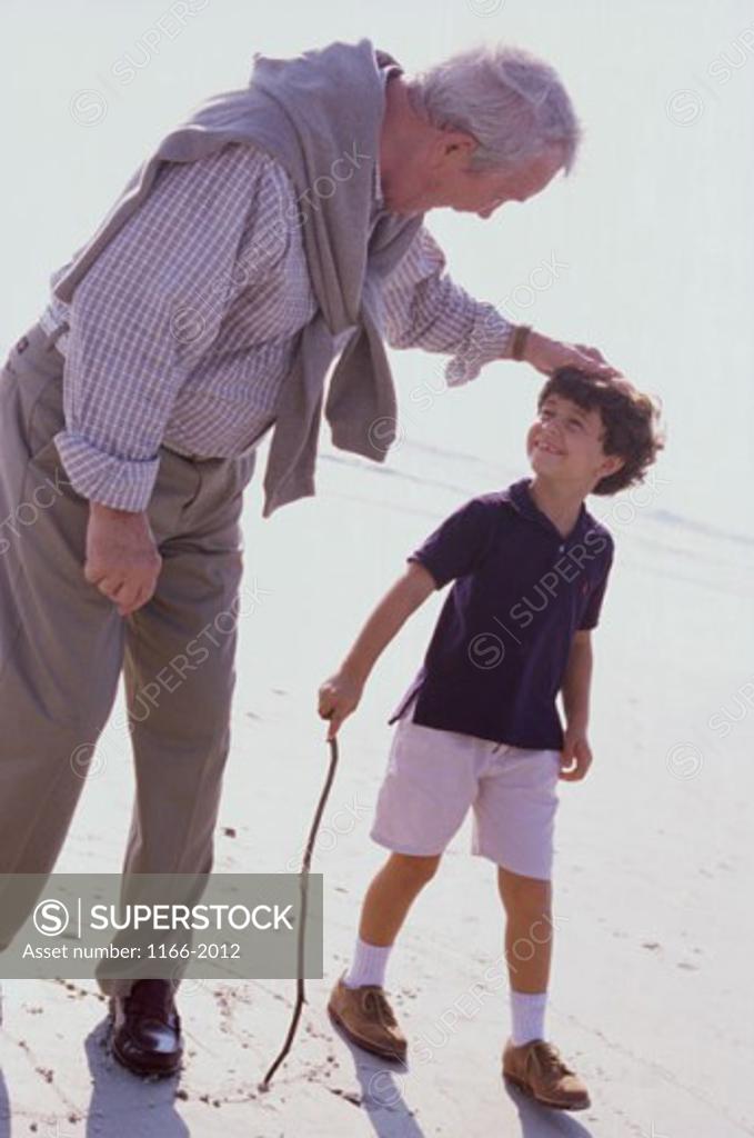 Stock Photo: 1166-2012 A child walking on the beach with his grandfather